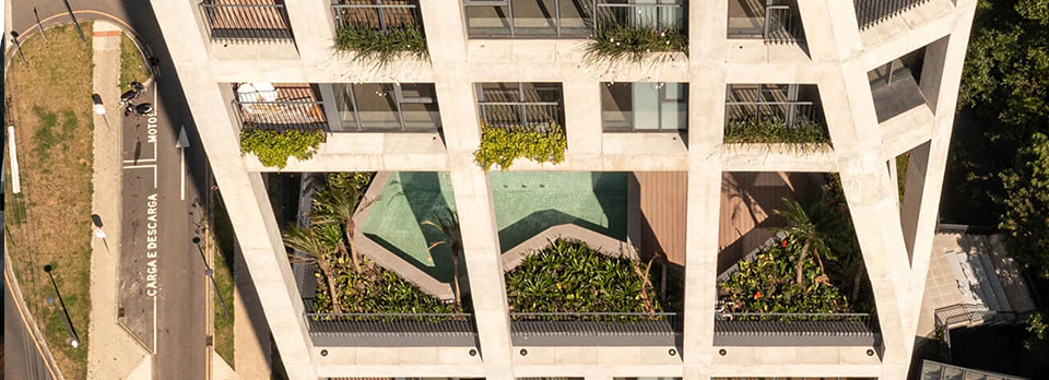 Profissional de sustentabilidade analisando projeto arquitetônico em edifício moderno com iluminação natural e vegetação interna.